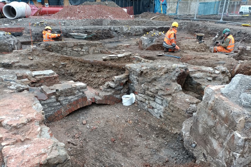 People working on an archaeological dig wearing bright orange jackets